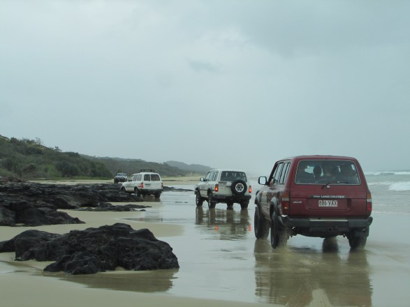 A traffic jam - the cars ahead waiting for the waves t go out before heading around the rocks